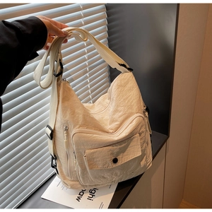 Detail of beige nylon crossbody bag showing multiple pockets and adjustable wide strap