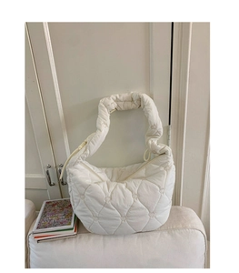 Détail d'un sac cabas matelassé crème avec motif de cœur rembourré dans un décor d'intérieur