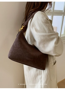 Detail of vintage coffee brown shoulder bag with gold hardware on a model indoors