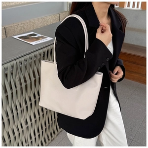 Detail view of cream white tote bag with lychee texture worn with a black blazer
