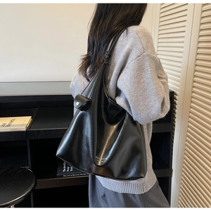 Détail du sac cabas noir brillant avec pochette ronde assortie et texte doré élégant