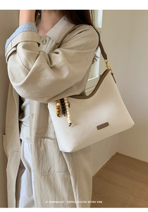 Close-up of minimalist cream tote bag with brown contrast strap and colorful wooden beads