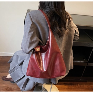 Détail du sac cabas en cuir bordeaux avec large bandoulière et poche latérale décorative