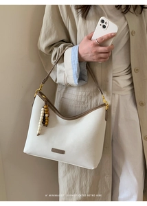 Model showcasing a vintage cream hobo bag with dark brown leather trim and beaded detail