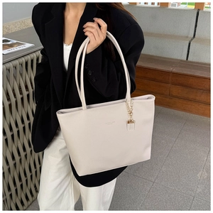 Close-up of litchi grain leather tote bag worn by model in business casual attire
