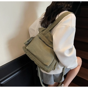 Detail view of army green canvas messenger bag with large front pocket and side pouch