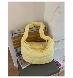 Détail du sac matelassé jaune clair avec broderies de cœurs et texture douce sur une chaise