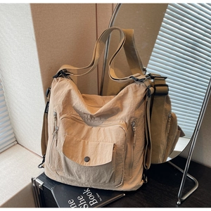 Detail of khaki nylon tote bag showing multi-pocket structure and adjustable shoulder strap