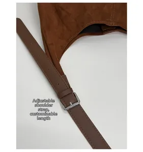 Detail of adjustable leather strap with silver buckle on brown suede dumpling bag