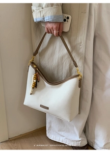 Detail of white litchi leather hobo bag with contrast brown trim and vintage wood beads