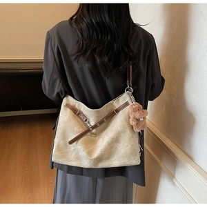 Detailed back view of large beige tote bag with brown leather straps and plush bear charm