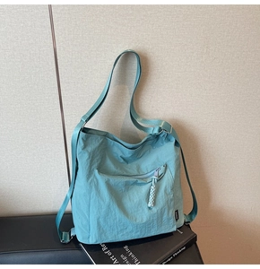 Detail of light blue nylon crossbody bag featuring textured fabric and rope zipper pull