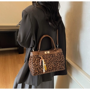 Dettaglio borsa leopardata in pelle scamosciata con manici marroni e ciondolo in legno