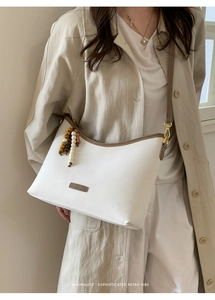Detailed view of retro white moon bag with brown trim and colorful wood bead tassel