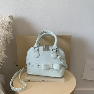 Detail of mint green shell bag featuring lychee texture and a matching decorative bow