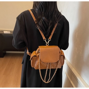 Mini sac à dos en cuir matelassé marron avec chaîne dorée porté par un mannequin
