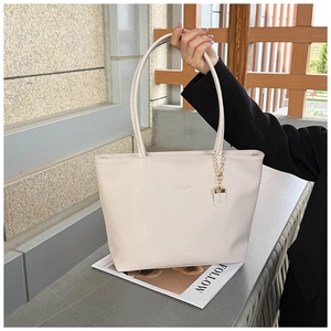 Macro view of creamy white tote bag featuring lychee grain leather and gold chain detail