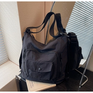 Close-up of black nylon hobo bag featuring multiple zippers and utility pockets