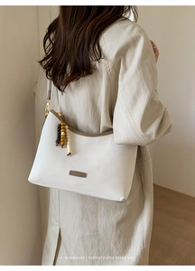White leather bucket bag detail with brown piping and colorful wooden bead tassels