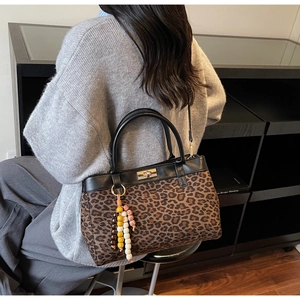 Dettaglio borsa leopardata in pelle scamosciata con chiusura a scatto e nappa di perle