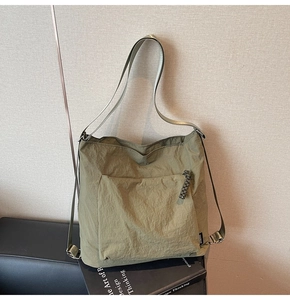 Detail of olive green nylon tote bag featuring crinkled texture and wide shoulder strap