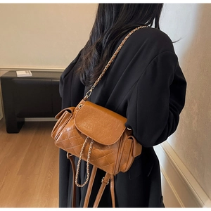 Détail d'un sac bandoulière matelassé marron avec chaîne dorée et poches latérales
