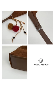 Détail du sac bandoulière en suédine avec pompon et bandoulière réglable à boucle