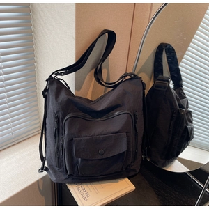 Detail of charcoal nylon tote bag showing durable texture and multi-pocket front design