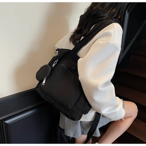 Minimalist black nylon backpack detail with matching round coin purse on the shoulder strap