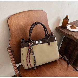 Close-up of retro khaki handbag with brown leather handles and woven tassel detail