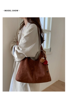 Détail du sac à bandoulière en daim marron foncé avec pompon bicolore en intérieur