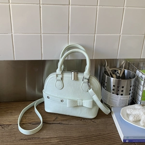 Detail view of mint green shell bag with bow decoration and smooth silver zipper