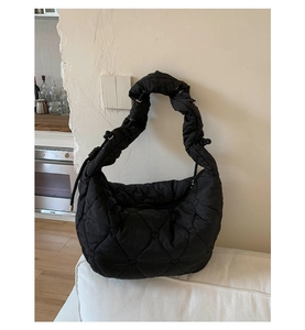 Détail d'un sac bouffant noir matelassé avec motif cœur et bandoulière à volants