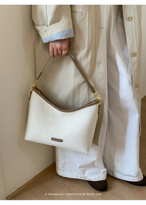 Close-up of retro ivory bucket bag with brown trim and minimalist metal logo plate