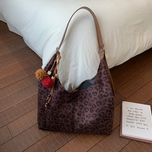 Détail du sac bandoulière léopard avec pompons en peluche et breloques perlées