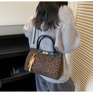 Dettaglio borsa in camoscio leopardato con chiusura dorata e ciondolo di perline