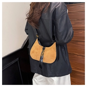 Detail of vintage crescent bag in tan suede and black leather on model wearing black coat