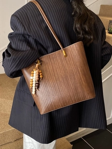 Borsa tote marrone intrecciata con ciondolo di perline su modella in abito formale