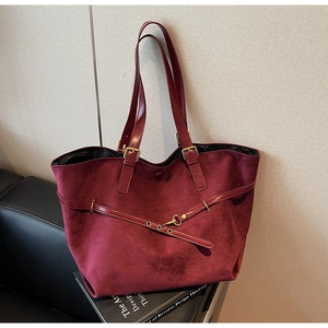 Detailed close-up of burgundy frosted leather tote with metallic buckle accents