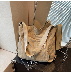 Detail of khaki nylon hobo bag with braided zipper and logo patch in home setting