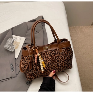 Elegante borsa leopardata con chiusura dorata e ciondolo di perline su sfondo bianco
