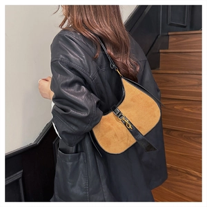 Detail of vintage suede crescent bag with leather trim and gold piston closure on shoulder