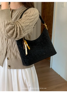 Detail of black suede hobo bag with colored wooden beads and gold hardware on model