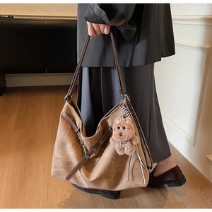 Detail of vintage brown suede tote bag featuring a cute plush bear charm for daily use