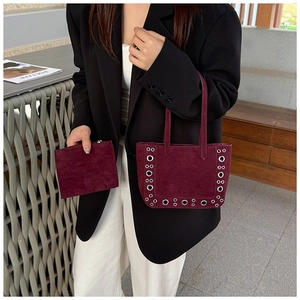 Détail du sac à main en daim bordeaux avec œillets métalliques et porte-monnaie assorti
