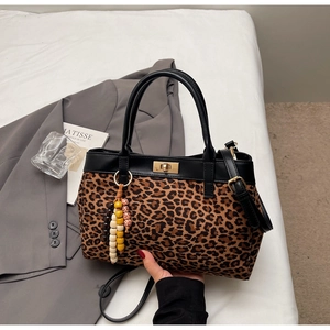 Dettaglio borsa tote leopardata con cinturini in pelle nera e chiusura a girello oro