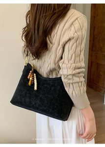 Detail of black retro suede shoulder bag with beaded fringe and bronze metal hardware