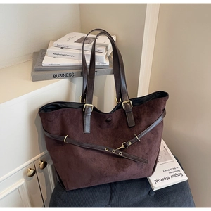 Macro shot of dark brown matte leather tote bag featuring detailed metal buckles and straps