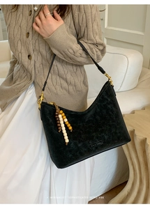 Detail of black suede hobo bag featuring vintage wooden bead tassel and gold hardware