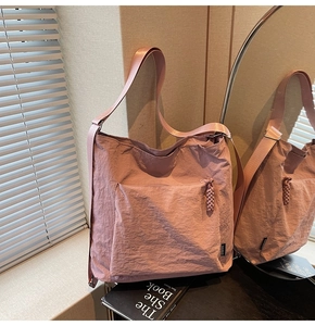 Detail of dusty pink nylon shoulder bag with pleated texture and woven zipper pull